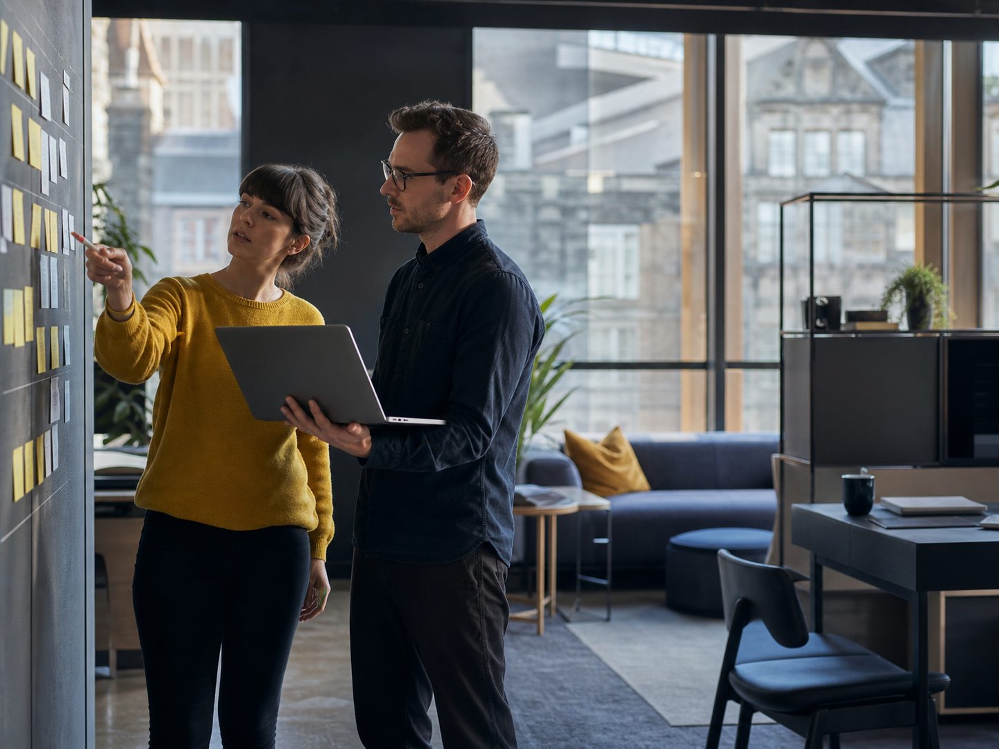 two professionals reviewing a workflow board in a modern studio